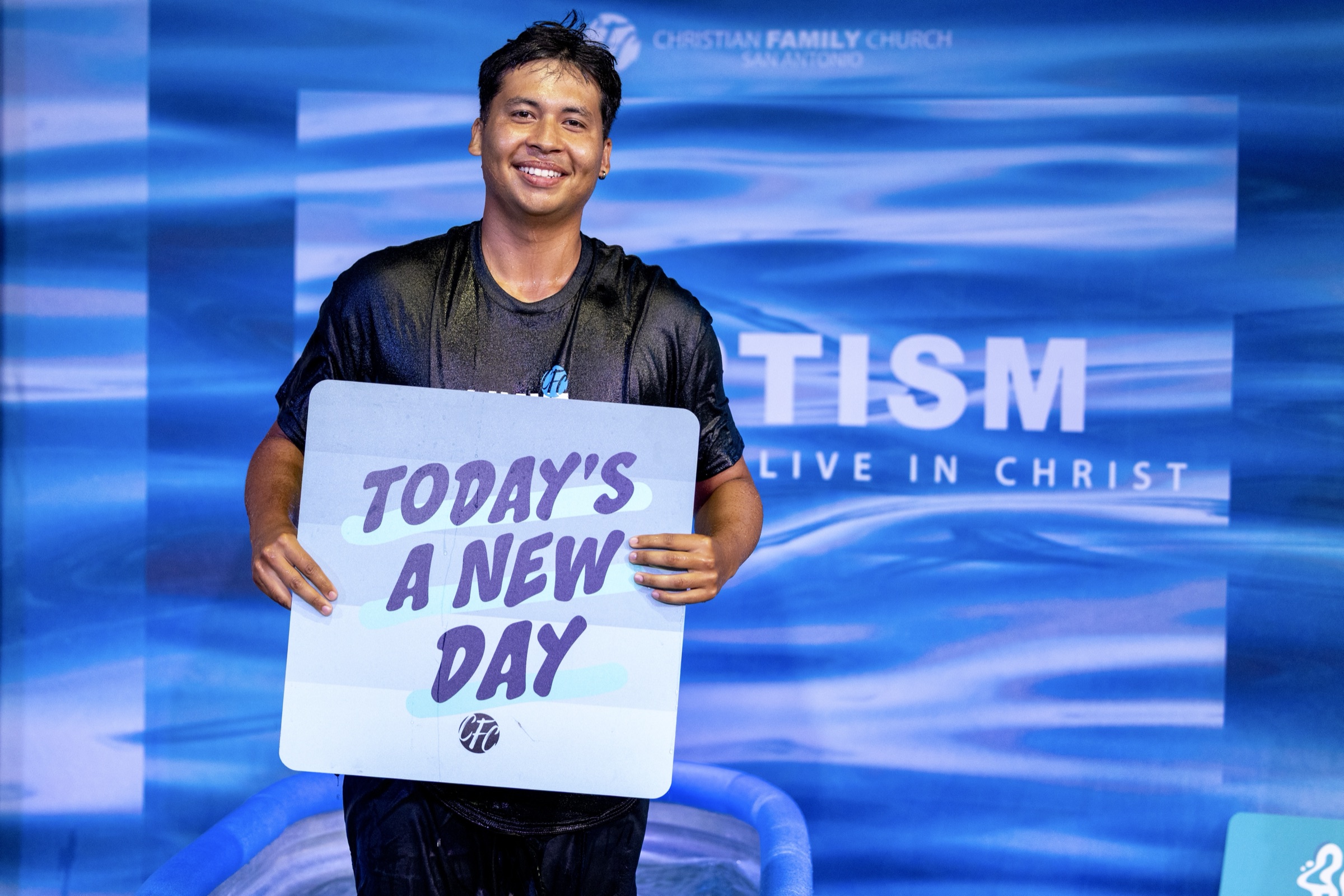 A man just baptized holding a sign that reads: today's a new day